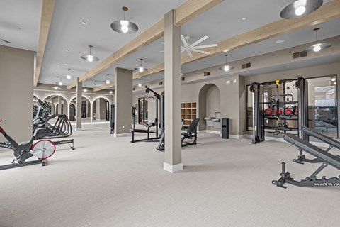 A gym with a variety of equipment including a rowing machine, a leg press machine, and a weight bench.
