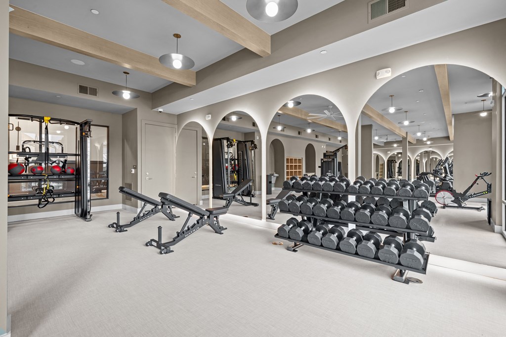 A gym with a variety of equipment including treadmills, weights, and exercise machines.