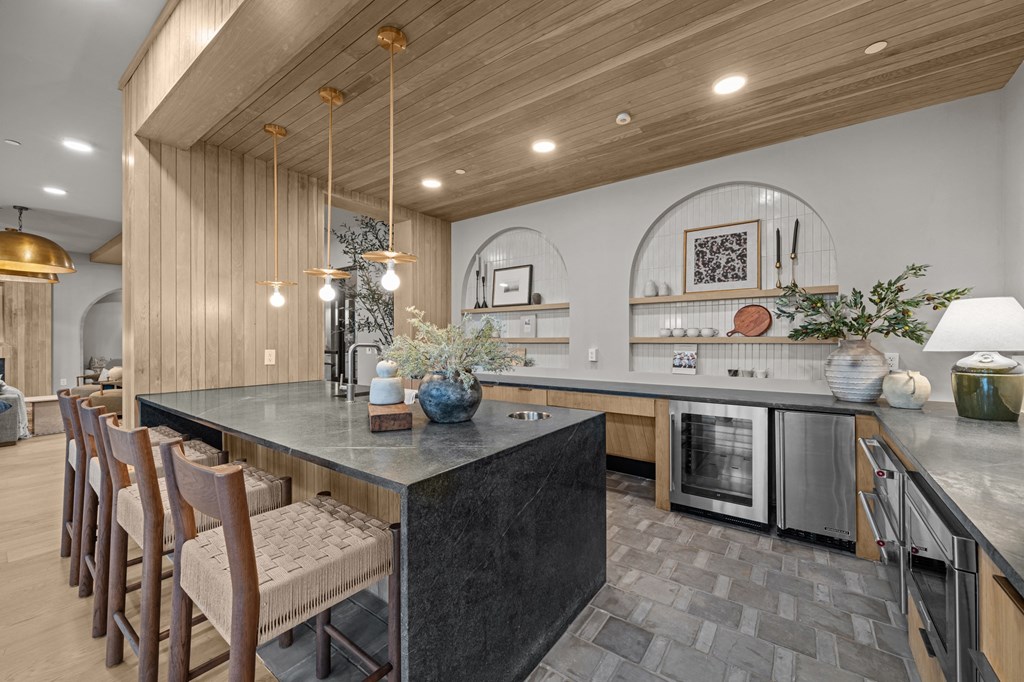 A modern kitchen with a dark granite countertop and wooden chairs.