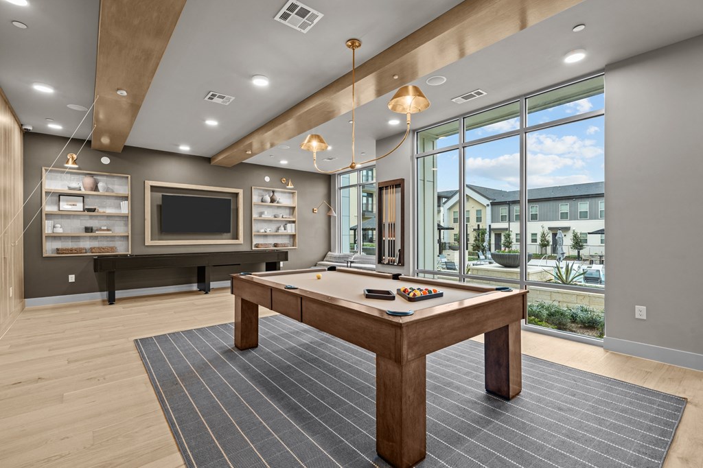 A billiard table is in the middle of a room with a large window.