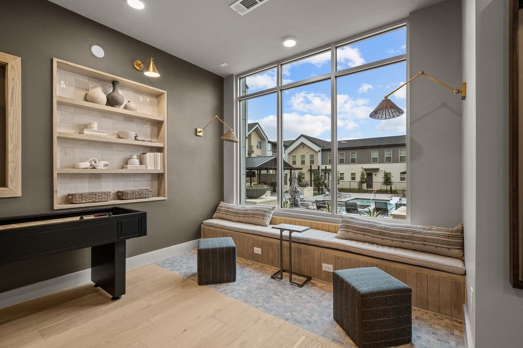 A room with a pool table and a view of a residential area outside the window.
