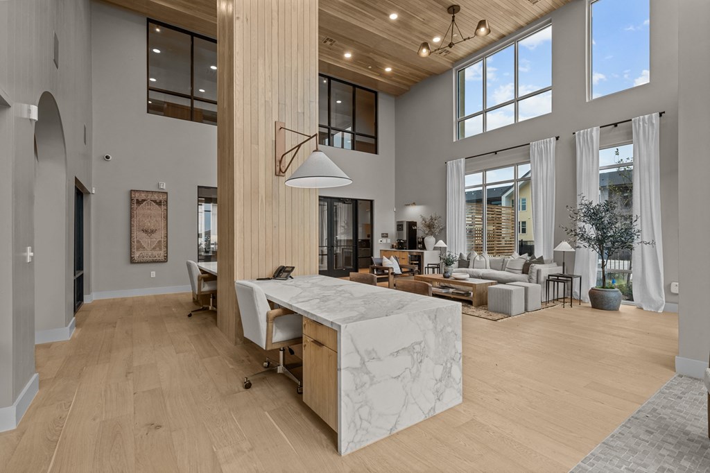 A large, modern kitchen with a marble island and wooden floors.