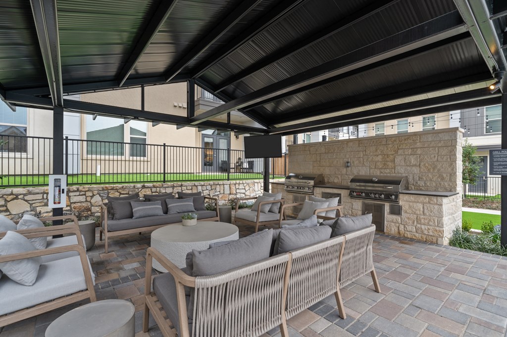 A patio with a stone fireplace and wicker furniture.