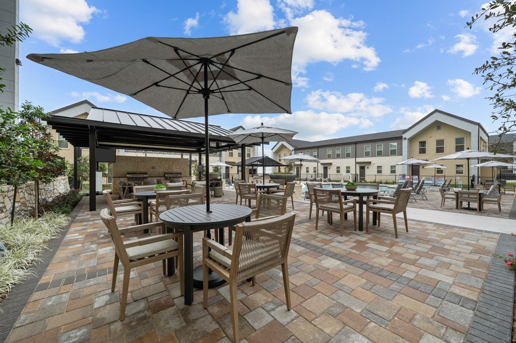 A patio with tables and chairs under umbrellas.
