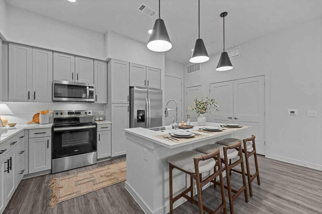 A modern kitchen with a dining table set for two.