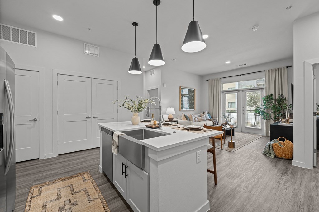 A modern kitchen with a large island and pendant lights.