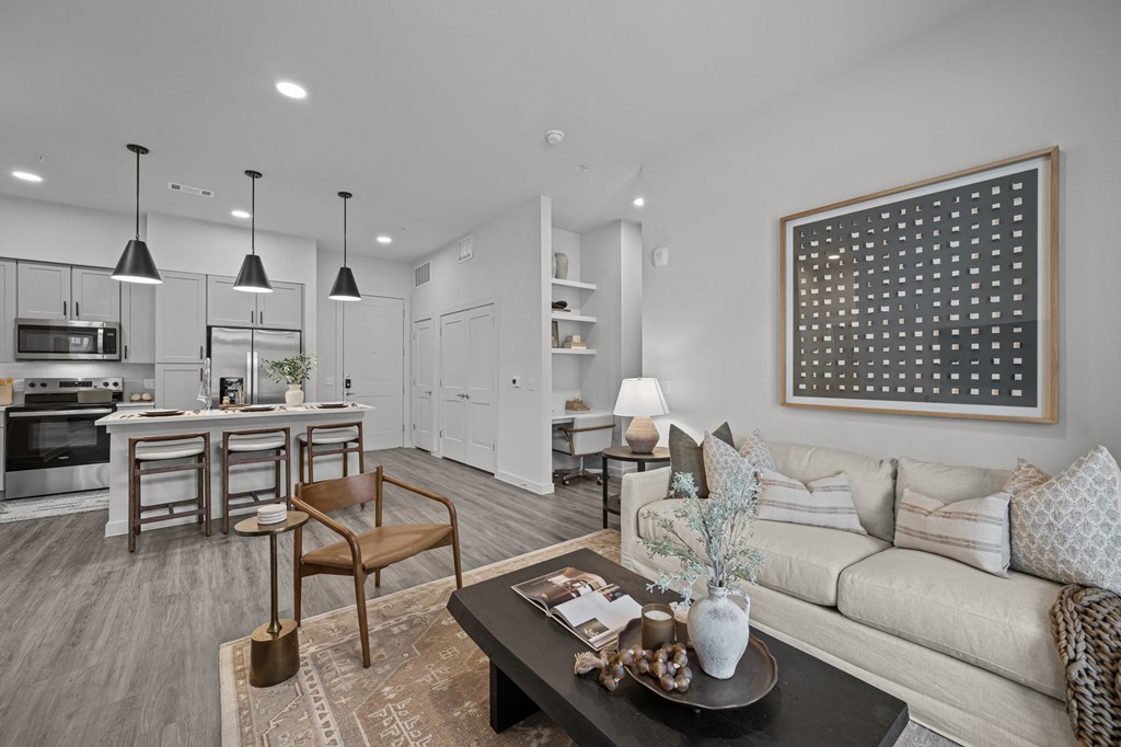 A modern living room with a grey couch, a coffee table, and a dining table with chairs.