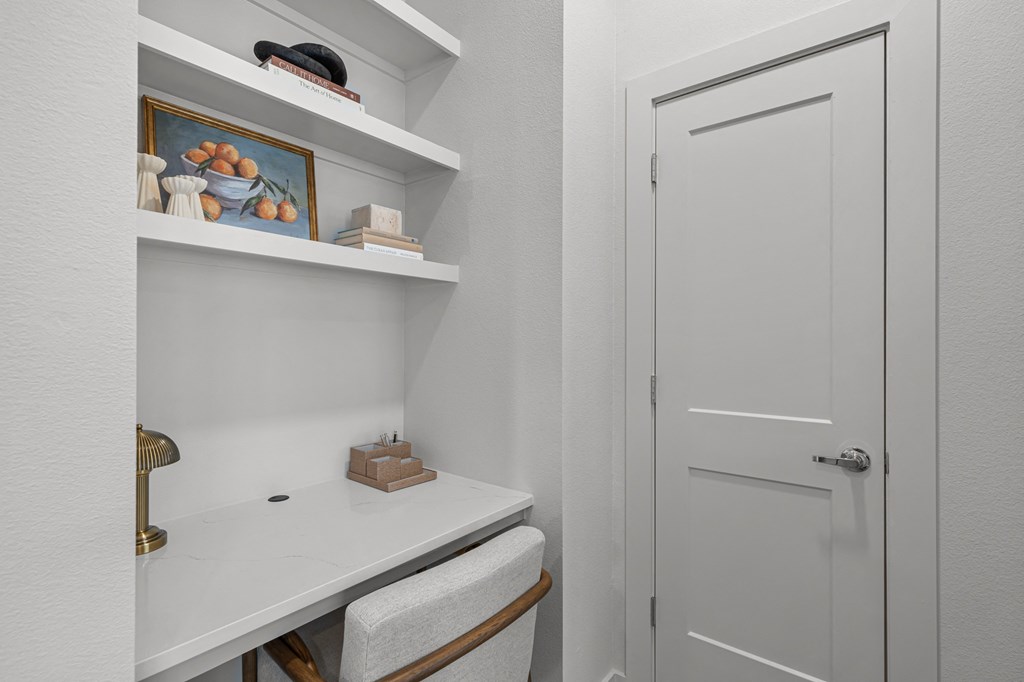 A white bathroom with a toilet, sink, and shelves.