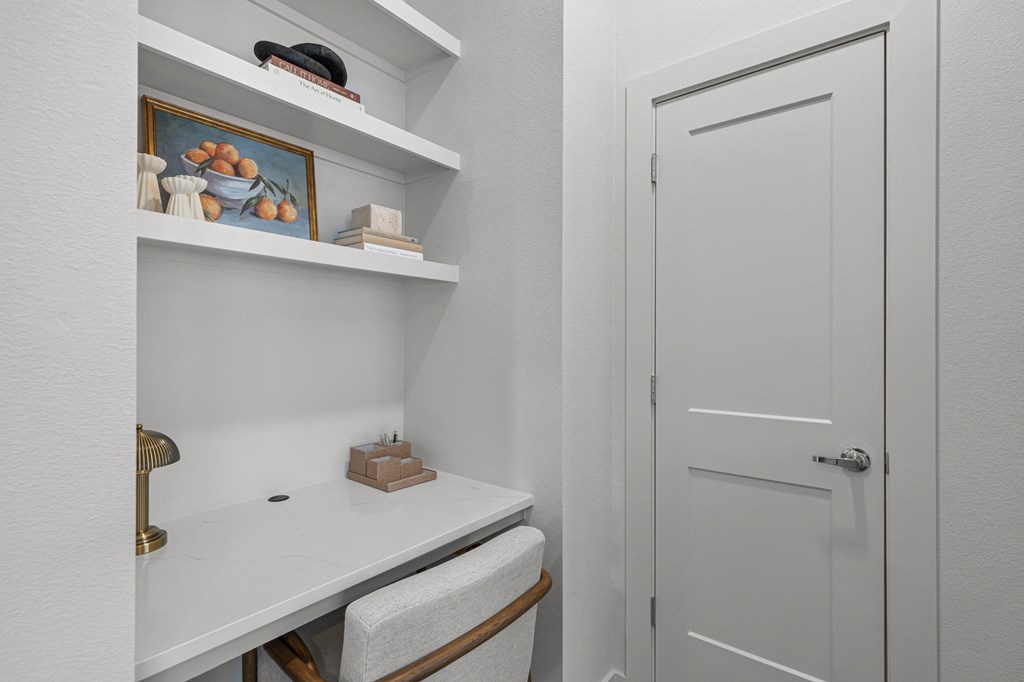 A white bathroom with a toilet, sink, and shelves.