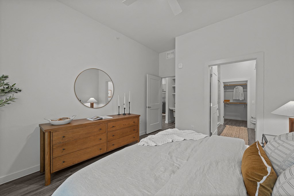 A bedroom with a bed, dresser, and mirror.