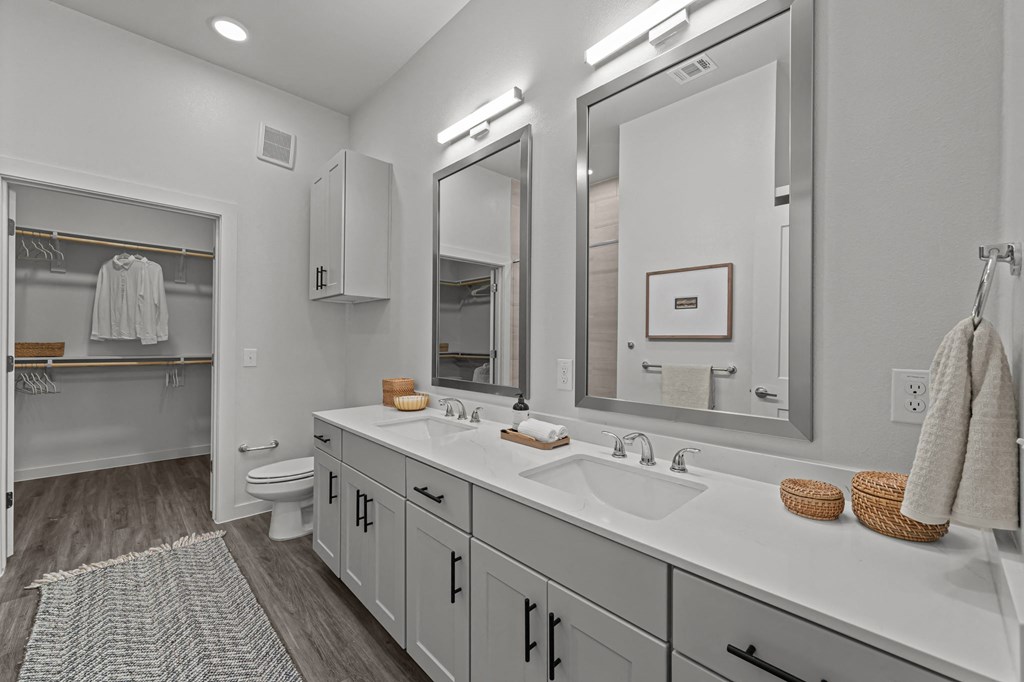 A bathroom with a white counter top and a large mirror.