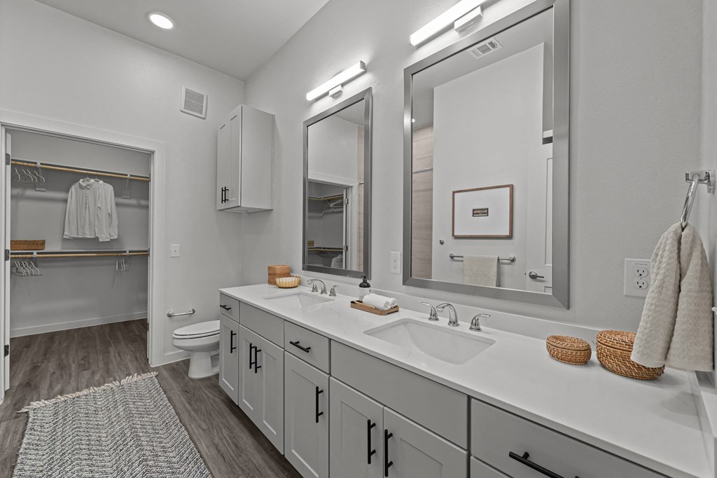 A bathroom with a white counter top and a large mirror.