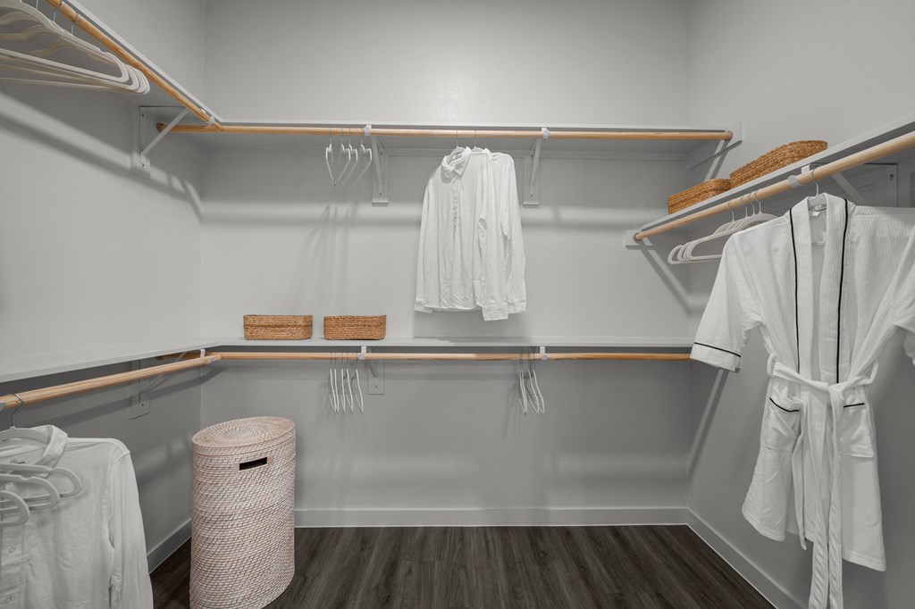 A white bathrobe is hanging on a rack in a white bathroom.