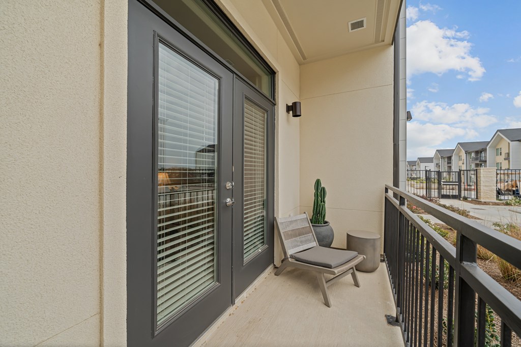 A patio with a chair and a cactus.