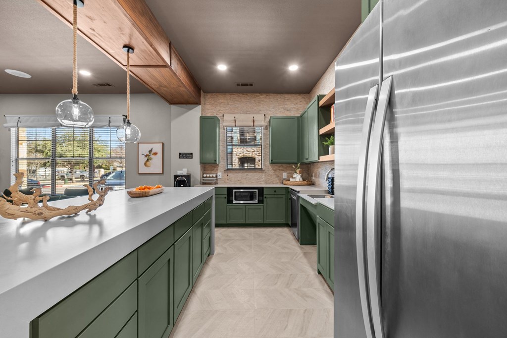 A modern kitchen with green cabinets and a stainless steel refrigerator.