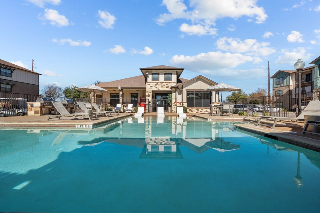 A large swimming pool in front of a building with a fountain in the middle.