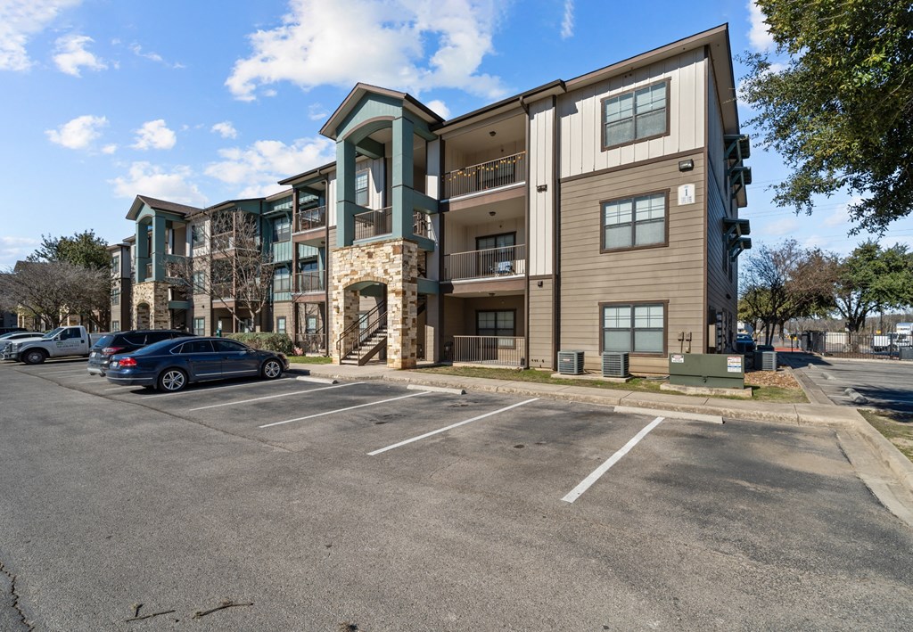 A parking lot in front of a modern apartment building.
