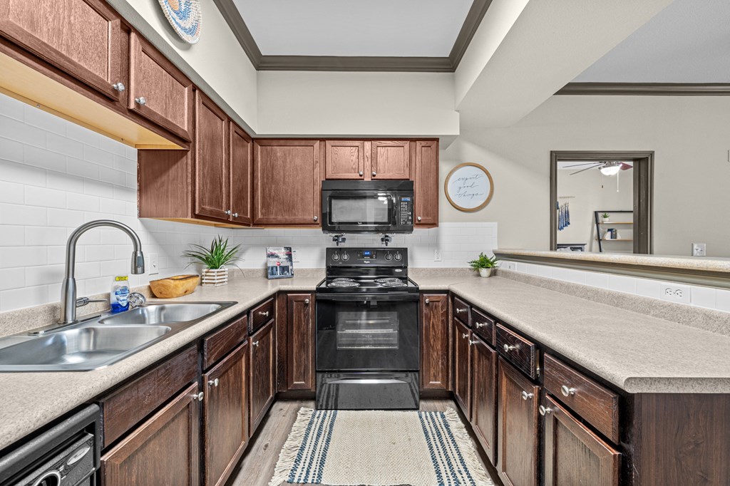 A kitchen with brown cabinets and a black stove top oven.