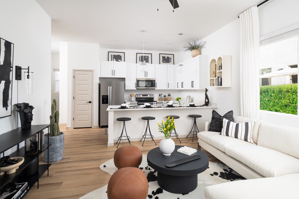 A modern living room with a kitchen in the background.