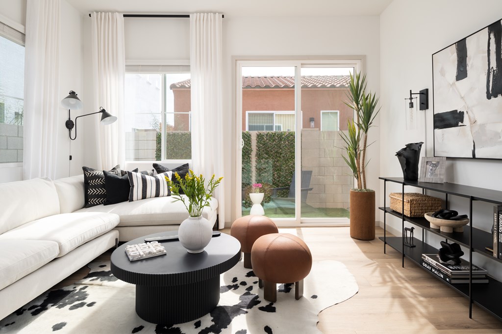 A living room with a white couch, a black coffee table, and a large painting on the wall.