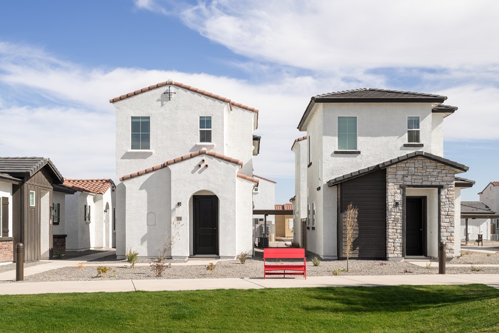 A white house with a red bench in front of it.