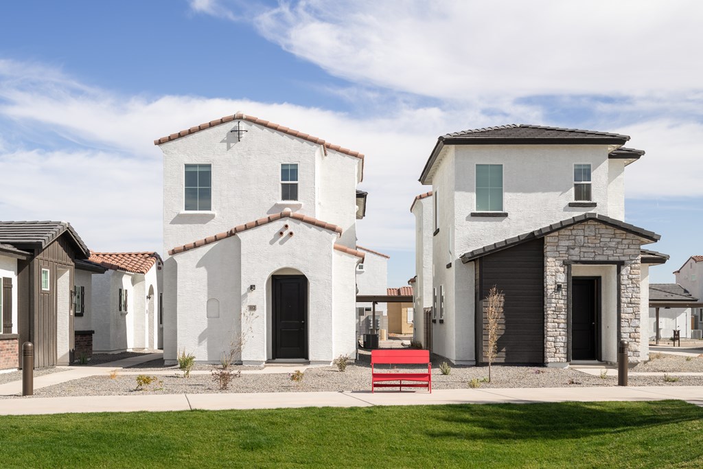 A white house with a red bench in front of it.