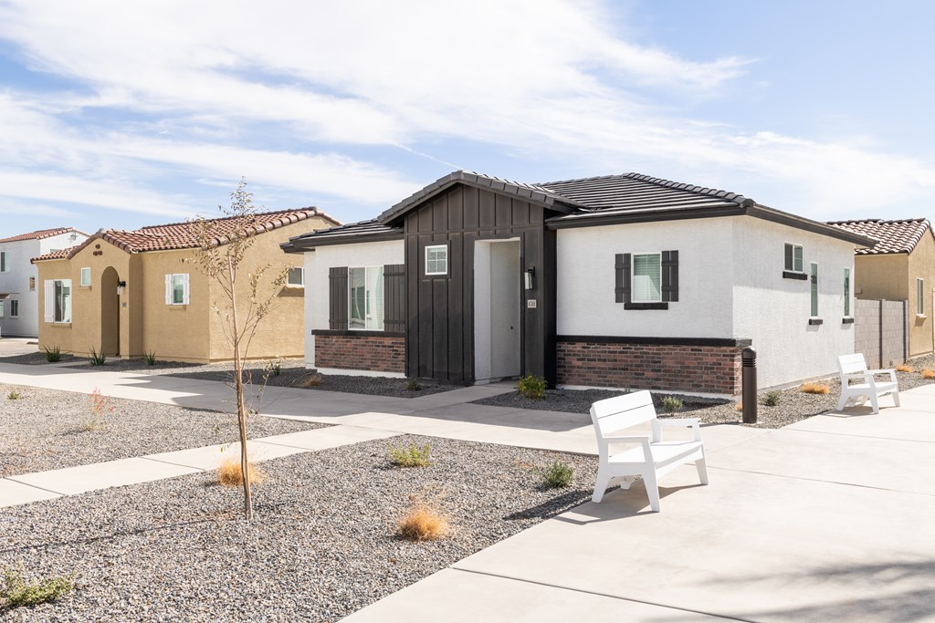 A white bench is in front of a house.
