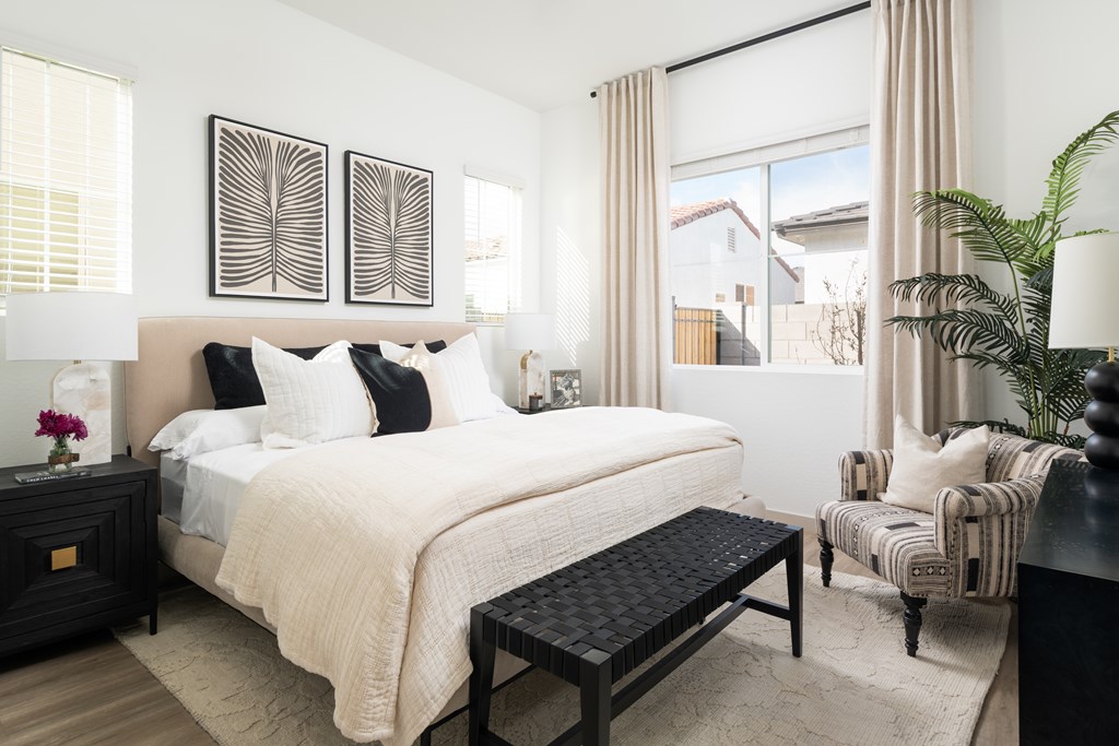 A bedroom with a large bed, a chair, and a potted plant.