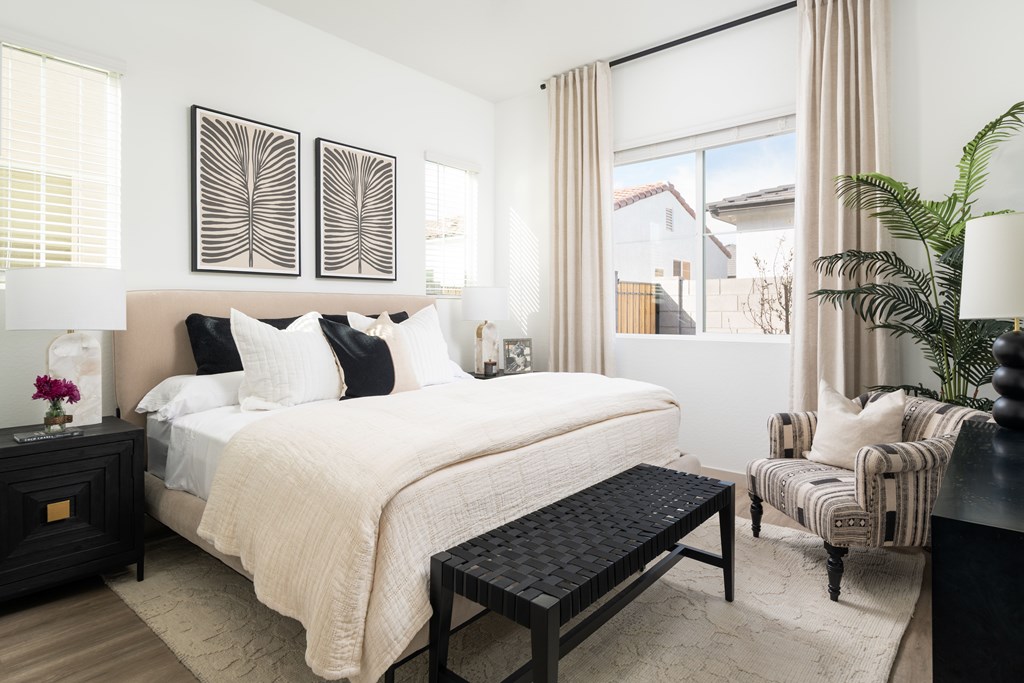 A bedroom with a large bed, a chair, and a potted plant.