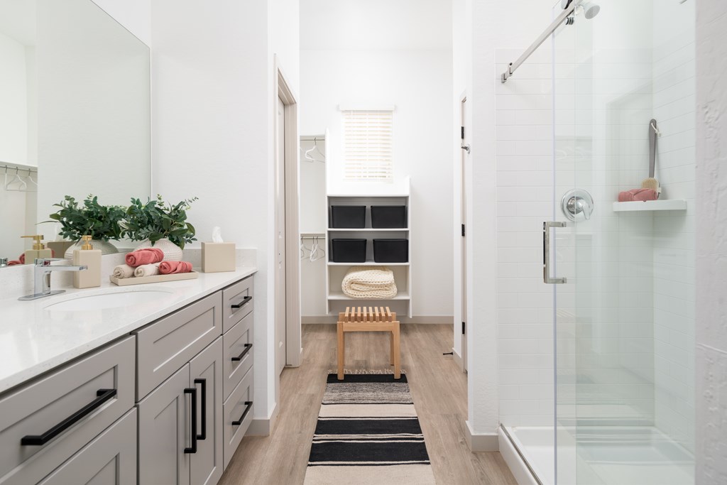 A bathroom with a white counter and a glass shower stall.