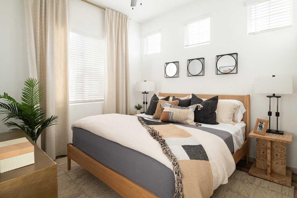 A bedroom with a bed, a plant, and a wooden side table.