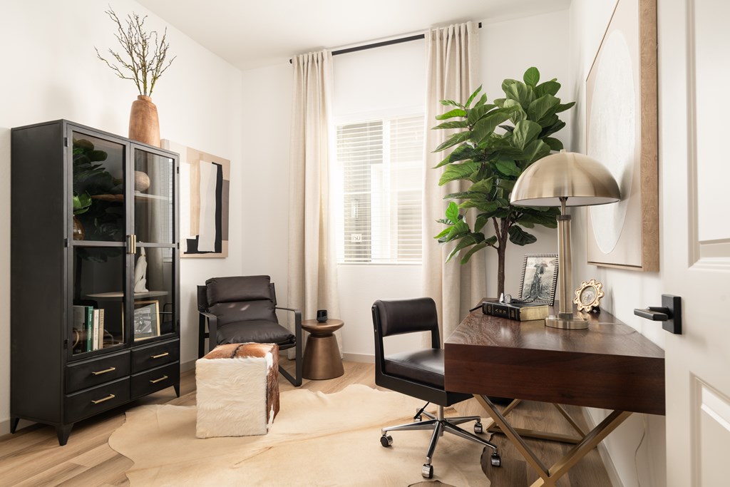 A black bookcase with a chair and a table with a lamp.