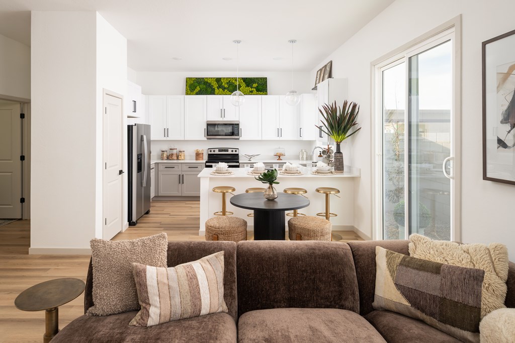A brown couch with a table in front of it and a kitchen in the background.