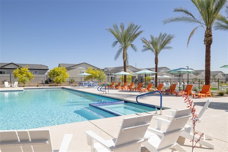 A pool surrounded by palm trees and lounge chairs.