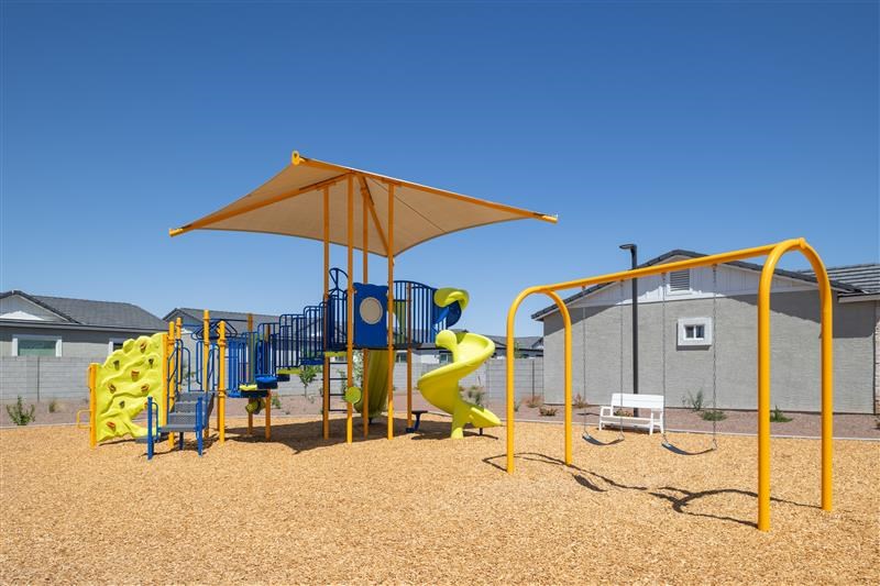 A playground with a yellow slide and a yellow umbrella.