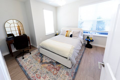 A bedroom with a white bed and a colorful rug.