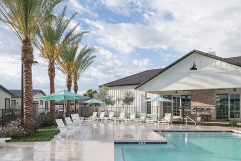 A pool area with palm trees and a white building.