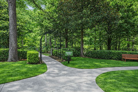 A walkway in a park with a bench on the right.