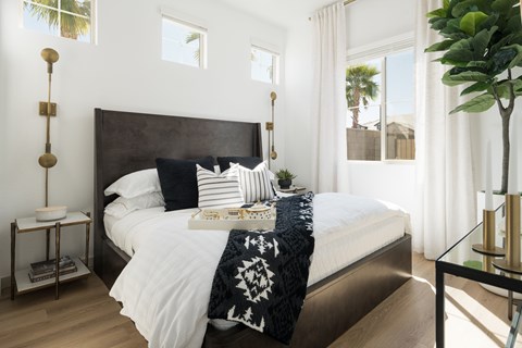 A bedroom with a large bed and a plant on the side table.