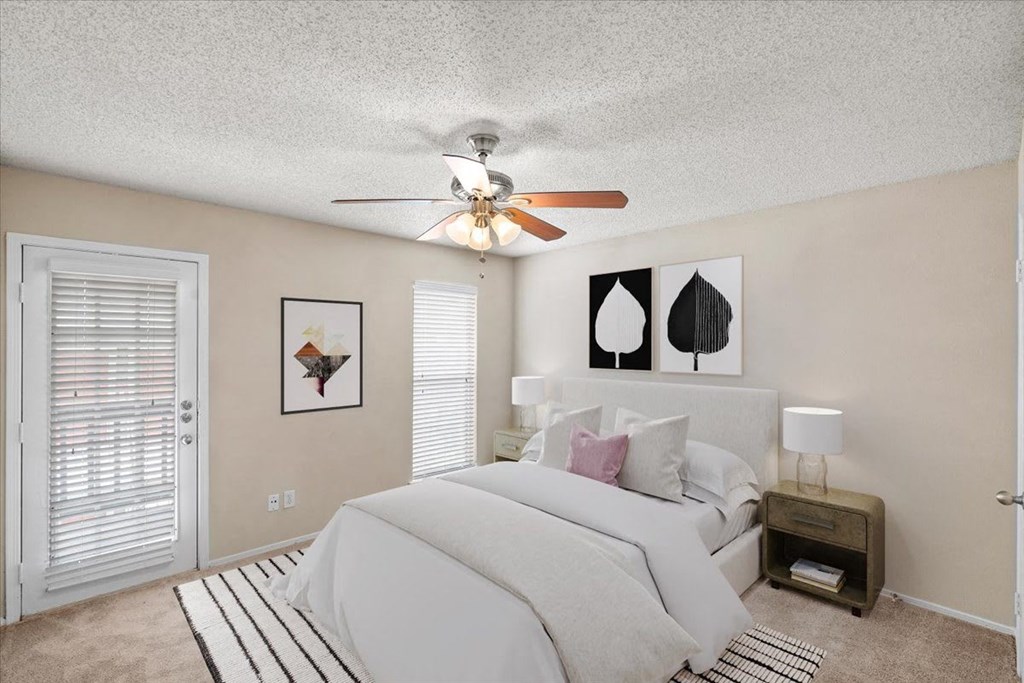 A bedroom with a large bed and a ceiling fan.