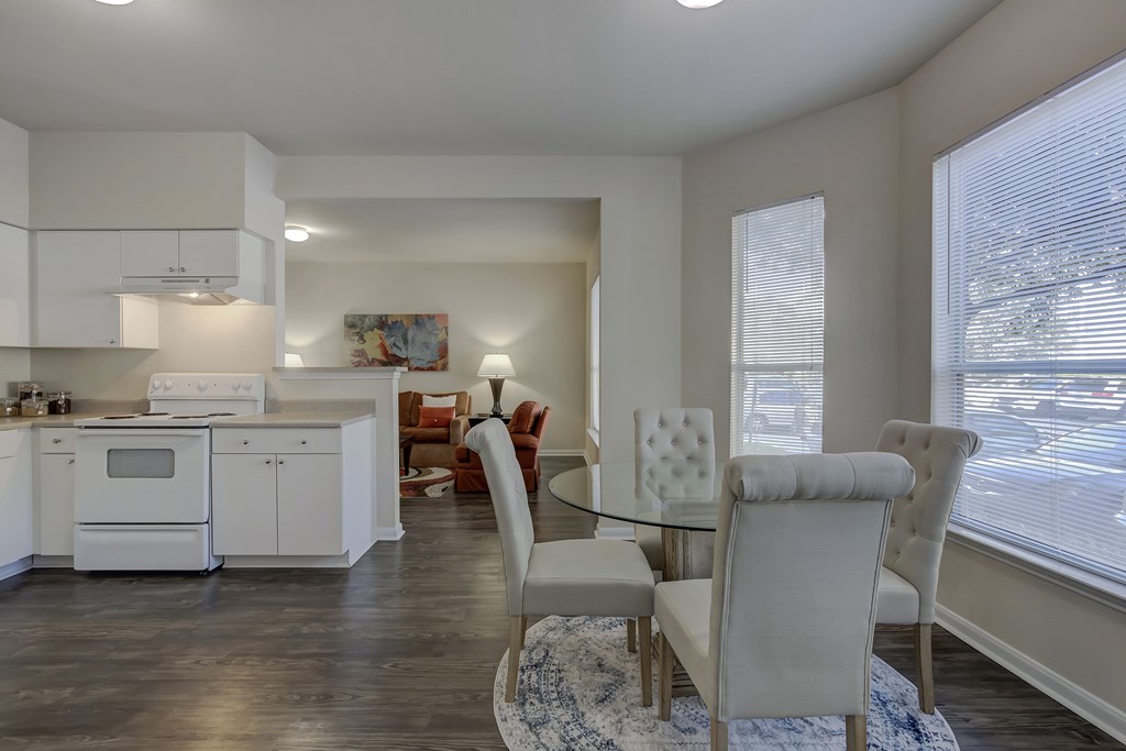 A modern kitchen with white cabinets and a dining area with a glass table.