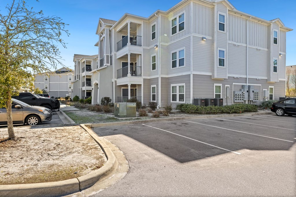 A large apartment complex with a parking lot in front.
