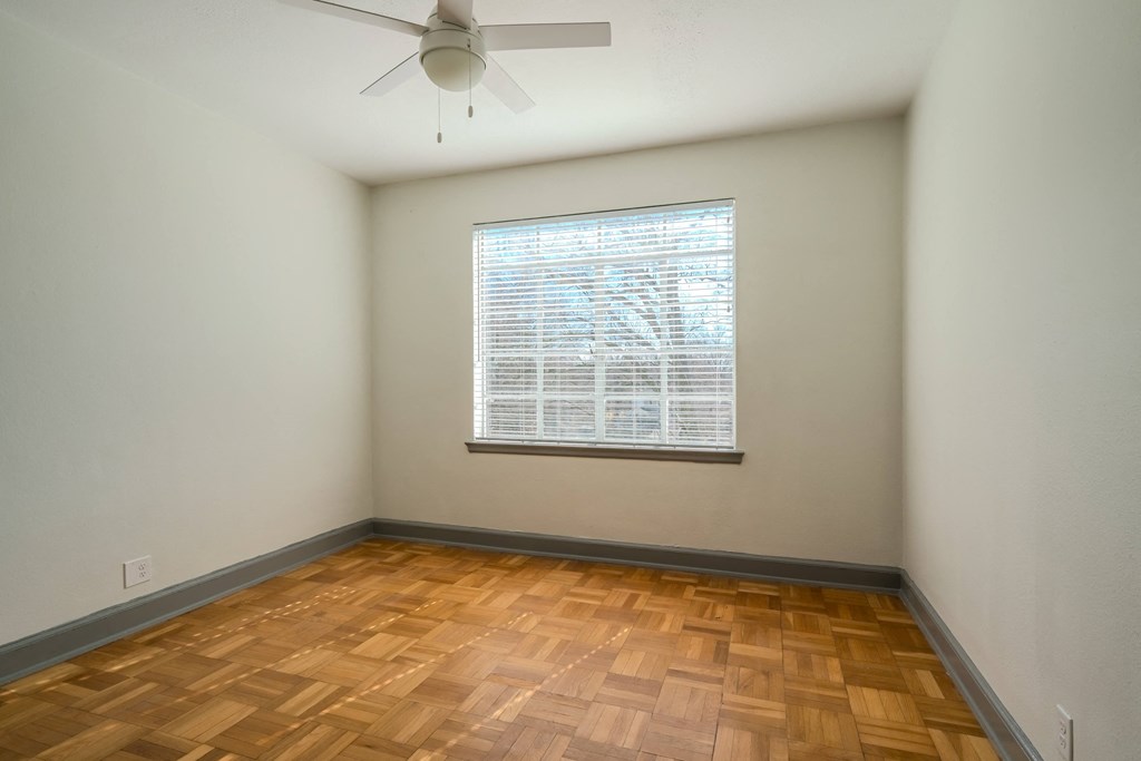a room with wood floors and a large window and a ceiling fan