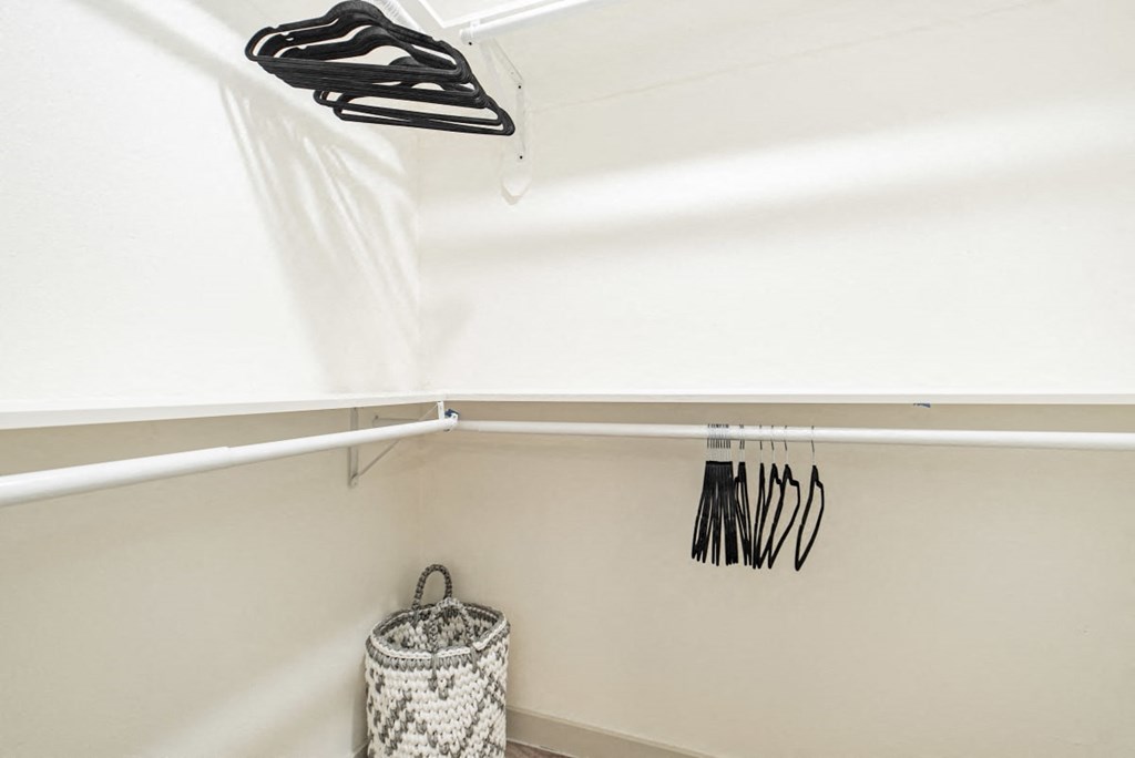 A white laundry basket sits under a clothes dryer.