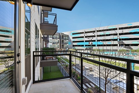 A balcony with a view of a pool and buildings.