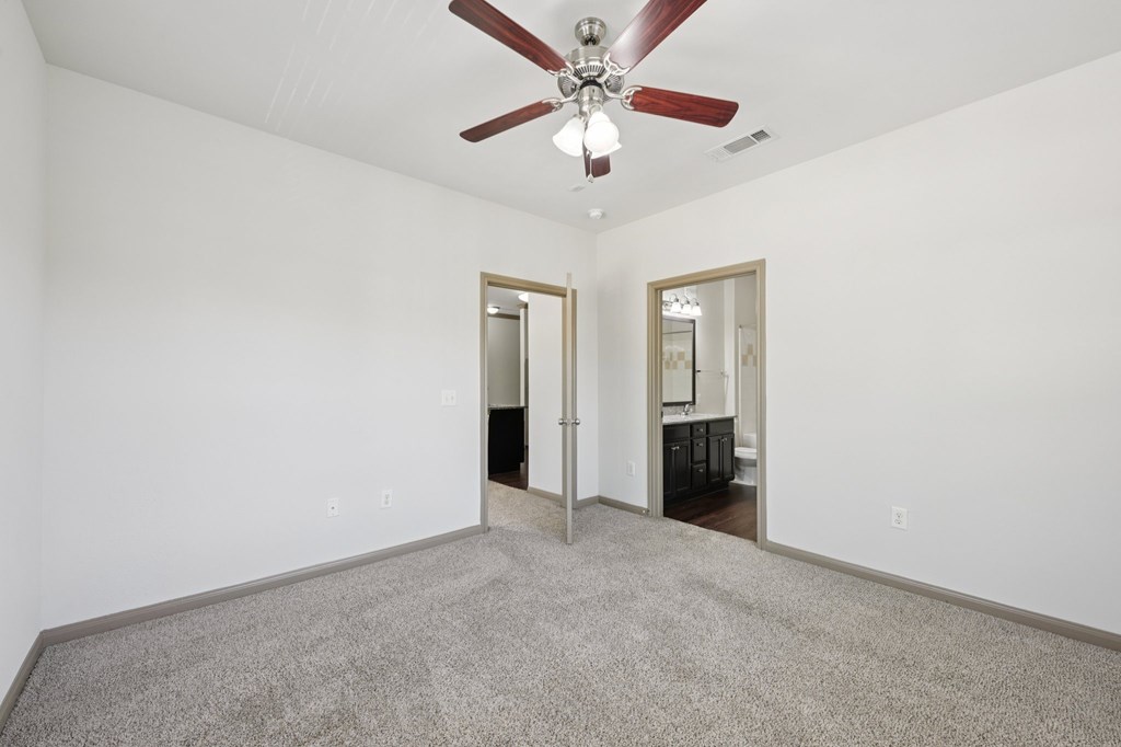 A room with a ceiling fan and carpeted floor.