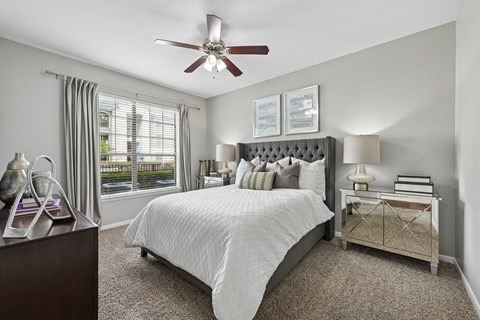 A bedroom with a bed, nightstand, and window.