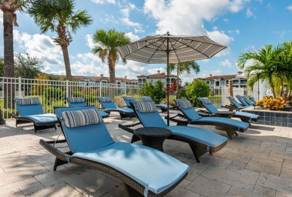 a pool with lounge chairs and an umbrella at the preserve at great pond apartments in windsor