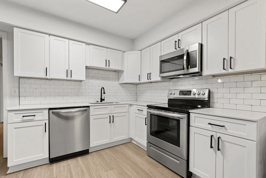 a white kitchen with stainless steel appliances and white cabinets