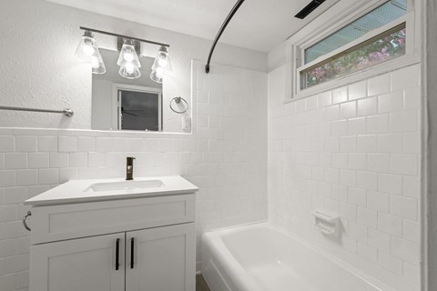 a white bathroom with a sink and a bath tub